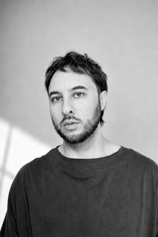 Man against a wall wearing a dark tshirt