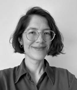 Headshot of a woman with glasses in a collared shirt smiling at the camera