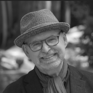 person wearing a hat and glasses, smiling into the camera